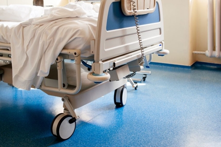 Empty modern hospital bed in a sunny room with a clean blue floor